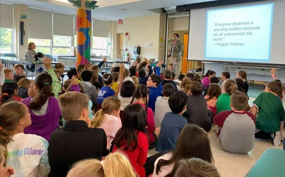 Sam Drazin presenting to students in a school cafeteria